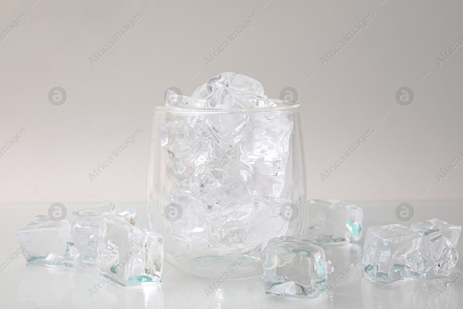 Photo of Refreshing water in glass with ice cubes on light background