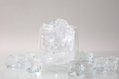 Photo of Refreshing water in glass with ice cubes on light background