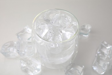 Photo of Refreshing water in glass with ice cubes on light background, closeup