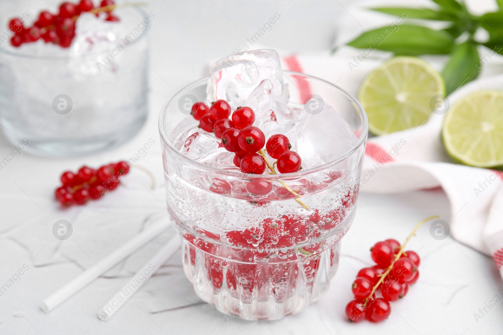 Photo of Refreshing water with red currants in glass on light table, closeup