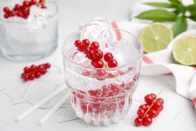 Photo of Refreshing water with red currants in glass on light table, closeup