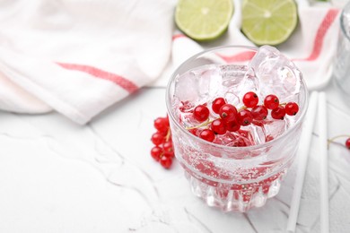 Photo of Refreshing water with red currants in glass on light table, closeup. Space for text