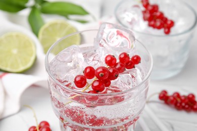 Photo of Refreshing water with red currants in glass on light table, closeup