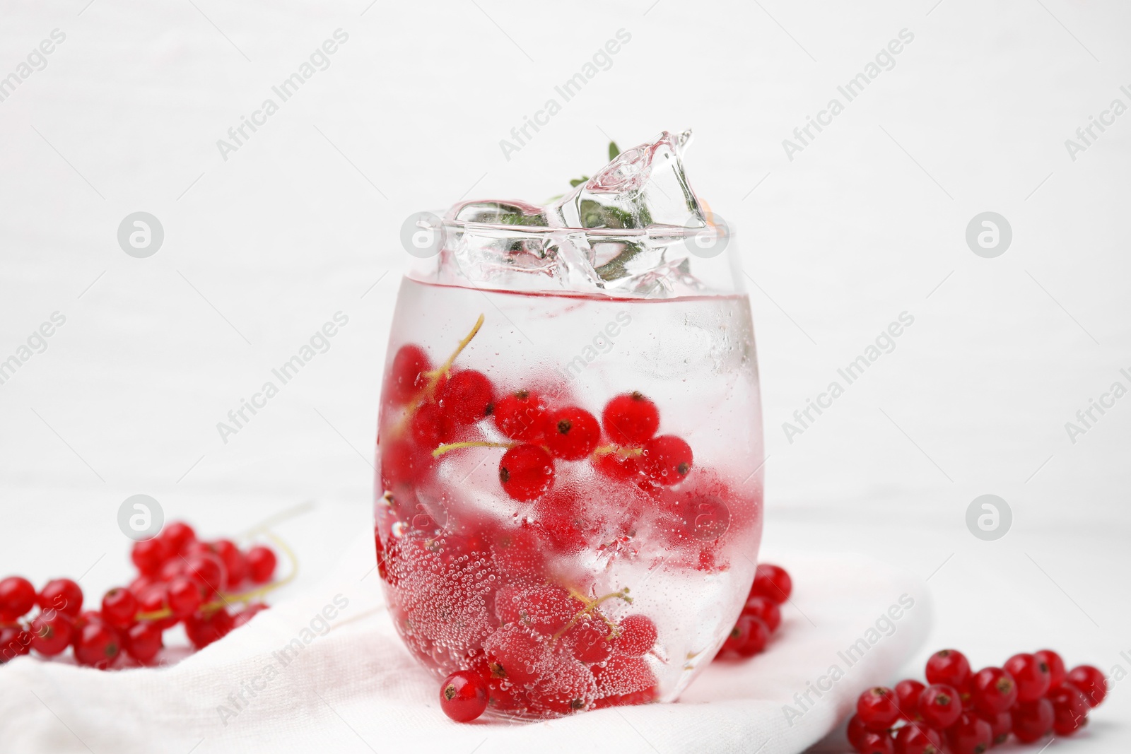 Photo of Refreshing water with red currants in glass on white table