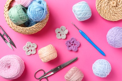 Photo of Different colorful yarns, crochet flowers, hook and scissors on pink background, flat lay