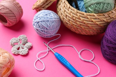 Photo of Different colorful yarns, crochet flower and hook on pink background