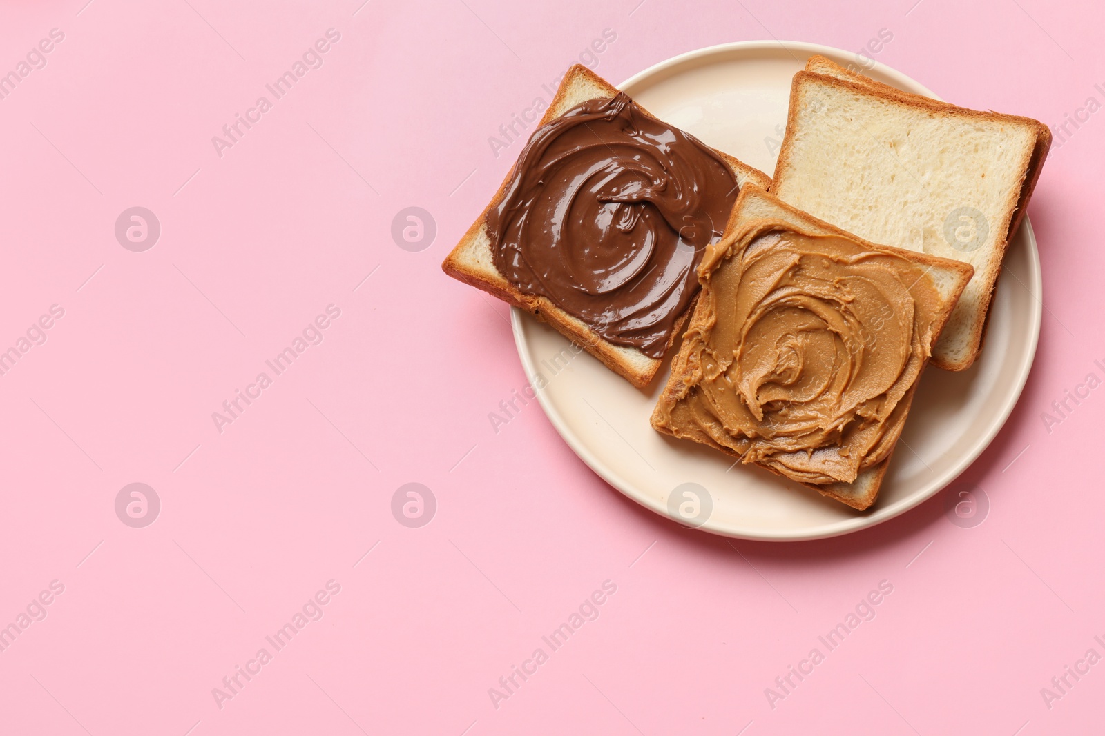 Photo of Delicious sandwiches with peanut butter and chocolate paste on pink table, top view. Space for text