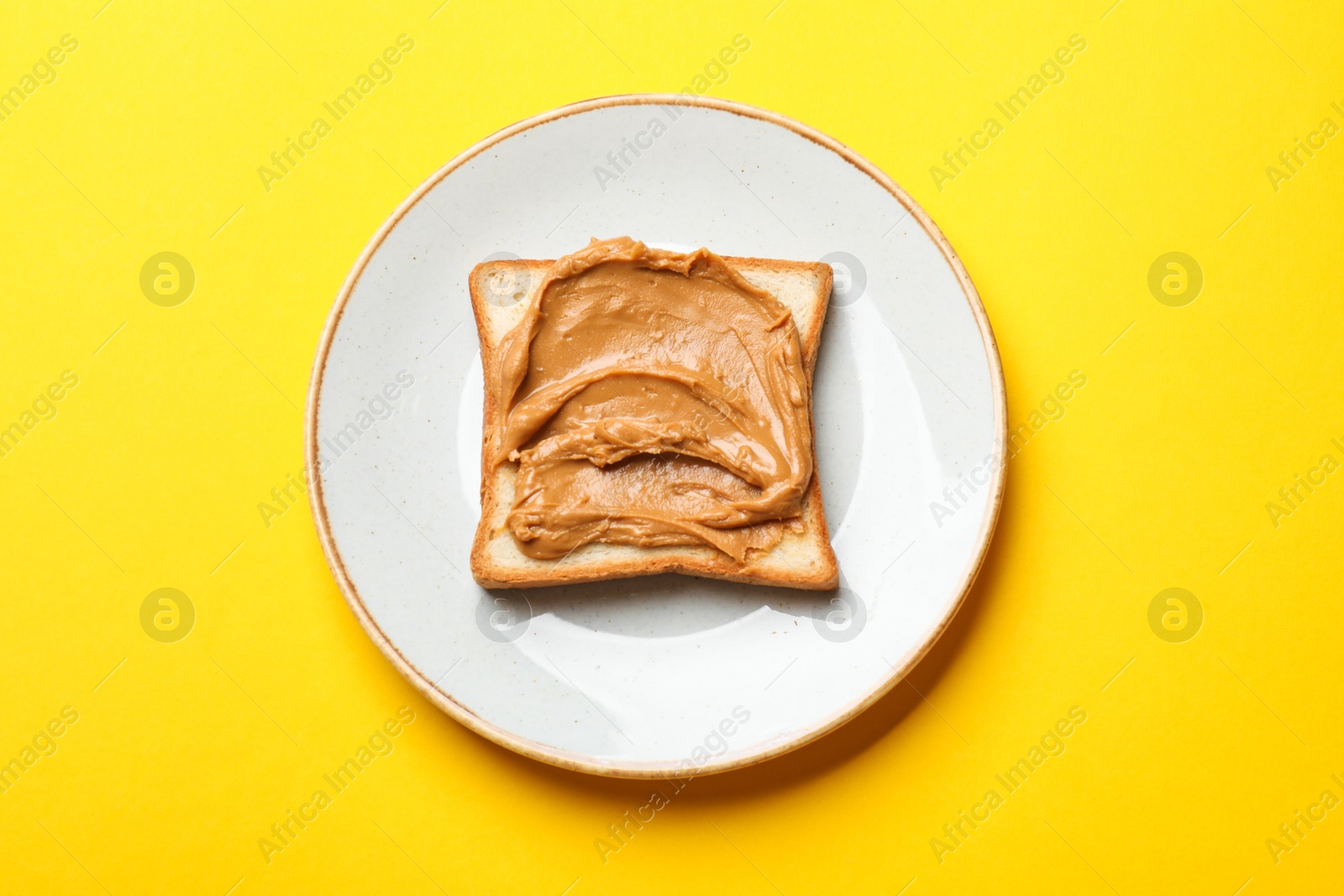 Photo of Delicious sandwich with peanut butter on yellow table, top view