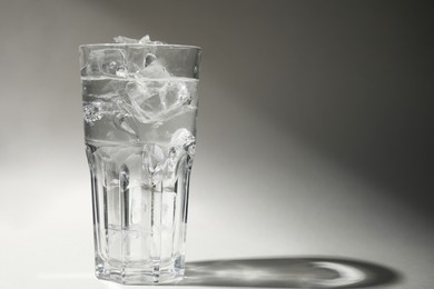 Photo of Refreshing water with ice in glass on grey background. Space for text