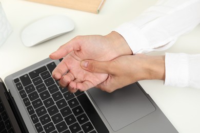 Photo of Carpal tunnel syndrome. Woman suffering from pain in wrist at desk, closeup