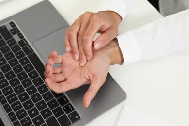 Photo of Carpal tunnel syndrome. Woman suffering from pain in wrist at desk, closeup