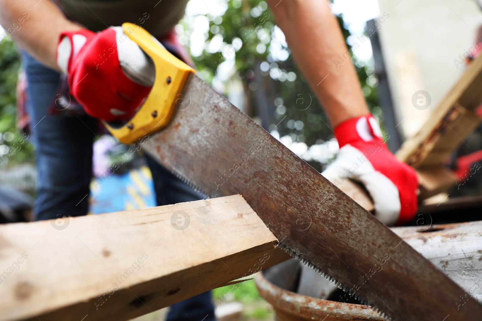 Photo of Man sawing wooden plank in backyard, closeup