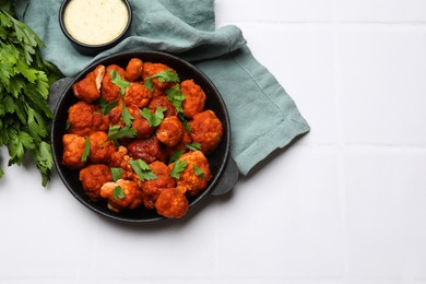 Photo of Baked cauliflower buffalo wings with parsley served on white tiled table, flat lay. Space for text