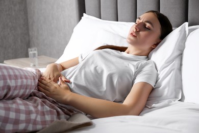 Woman suffering from menstrual pain on bed at home