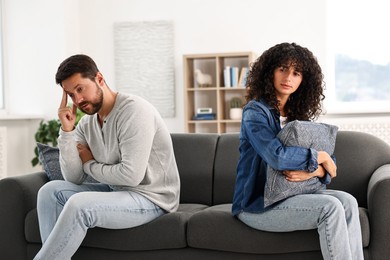 Photo of Emotional couple having quarrel on sofa at home. Relationship problems