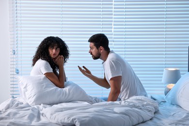 Photo of Emotional couple arguing in bedroom at night. Relationship problems