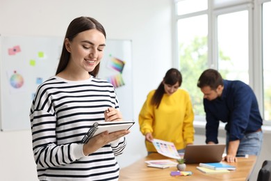 Photo of Portrait of happy young designer with notebook in office