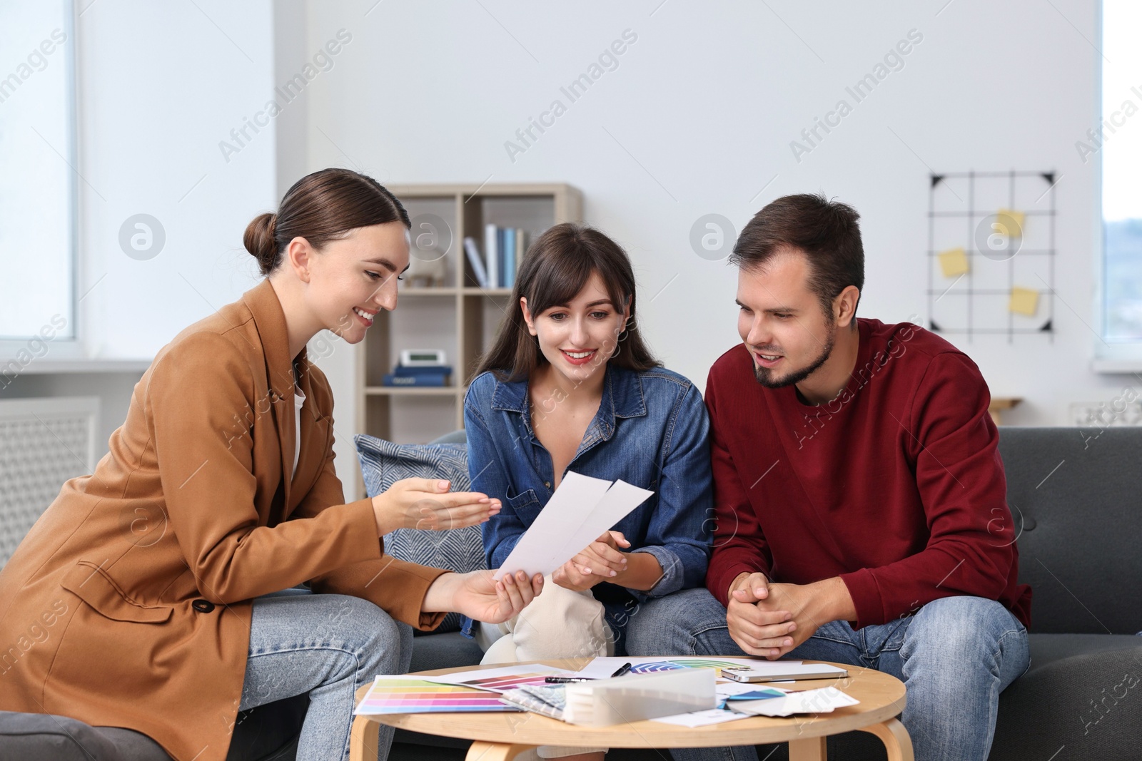 Photo of Designer discussing project with clients at table in office