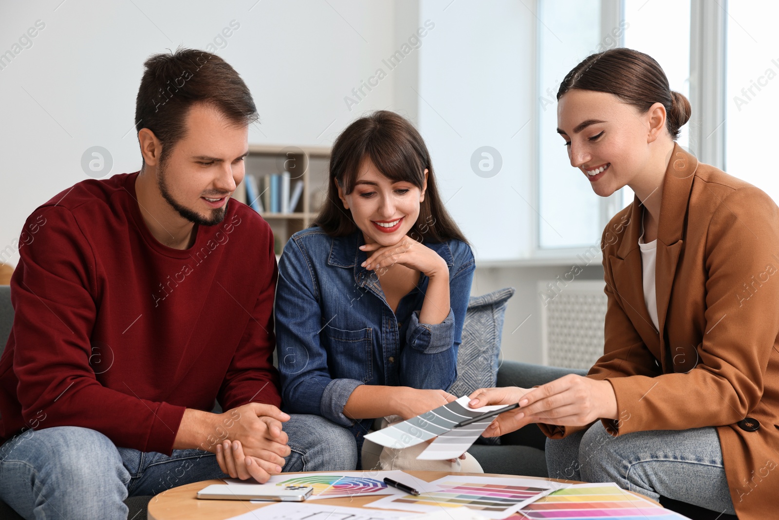 Photo of Designer discussing project with clients at table in office