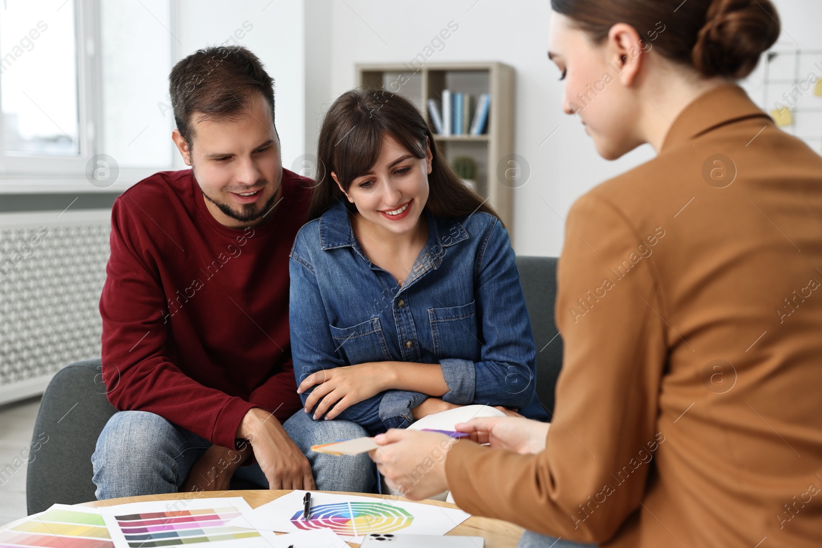 Photo of Designer discussing project with clients at table in office