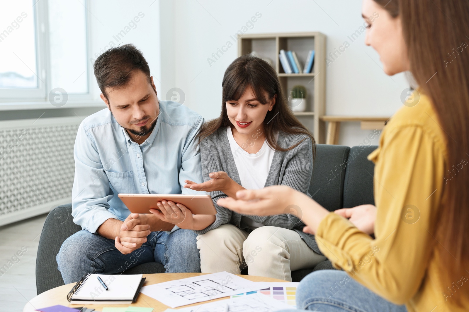 Photo of Designer discussing project with clients at table in office