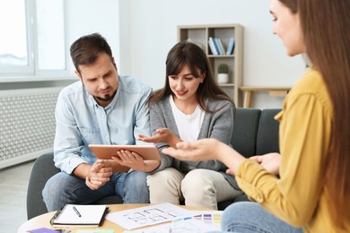 Designer discussing project with clients at table in office