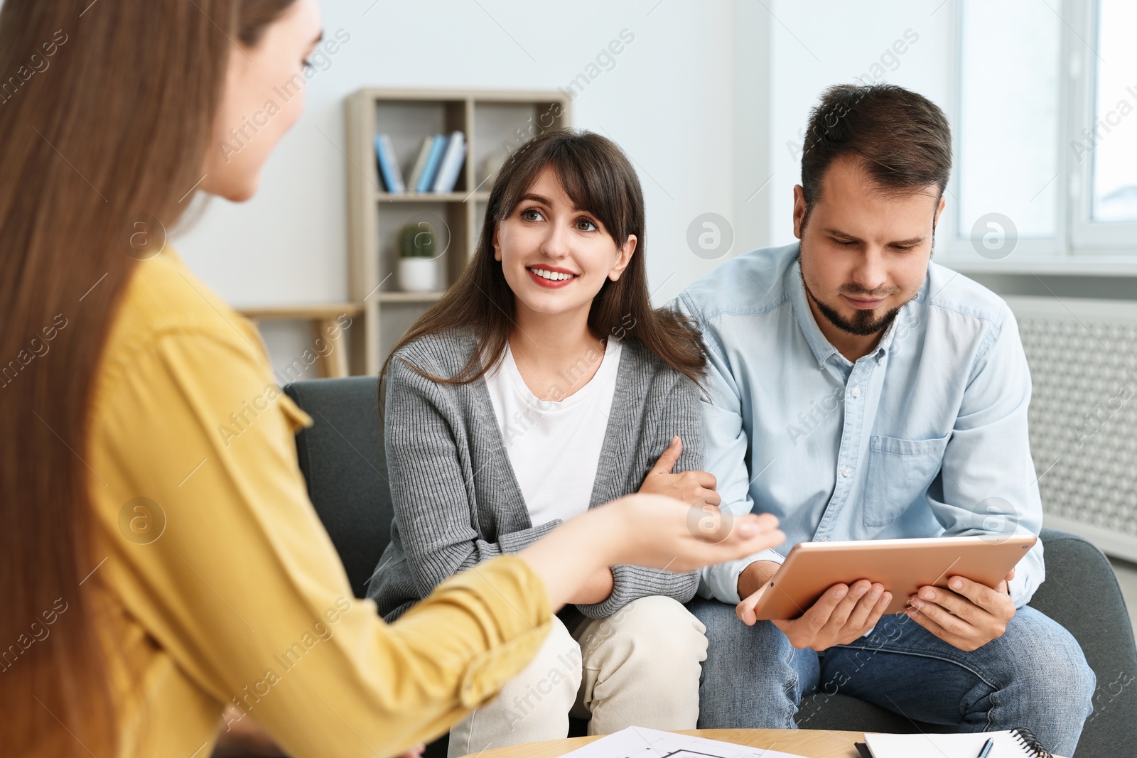 Photo of Designer discussing project with clients at table in office