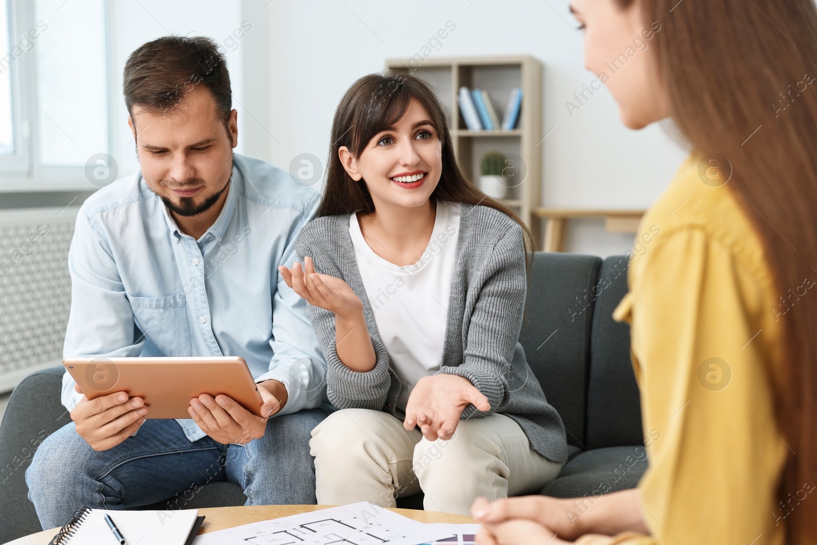 Photo of Designer discussing project with clients at table in office