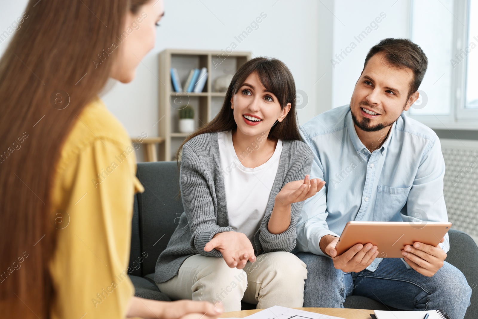 Photo of Designer discussing project with clients at table in office