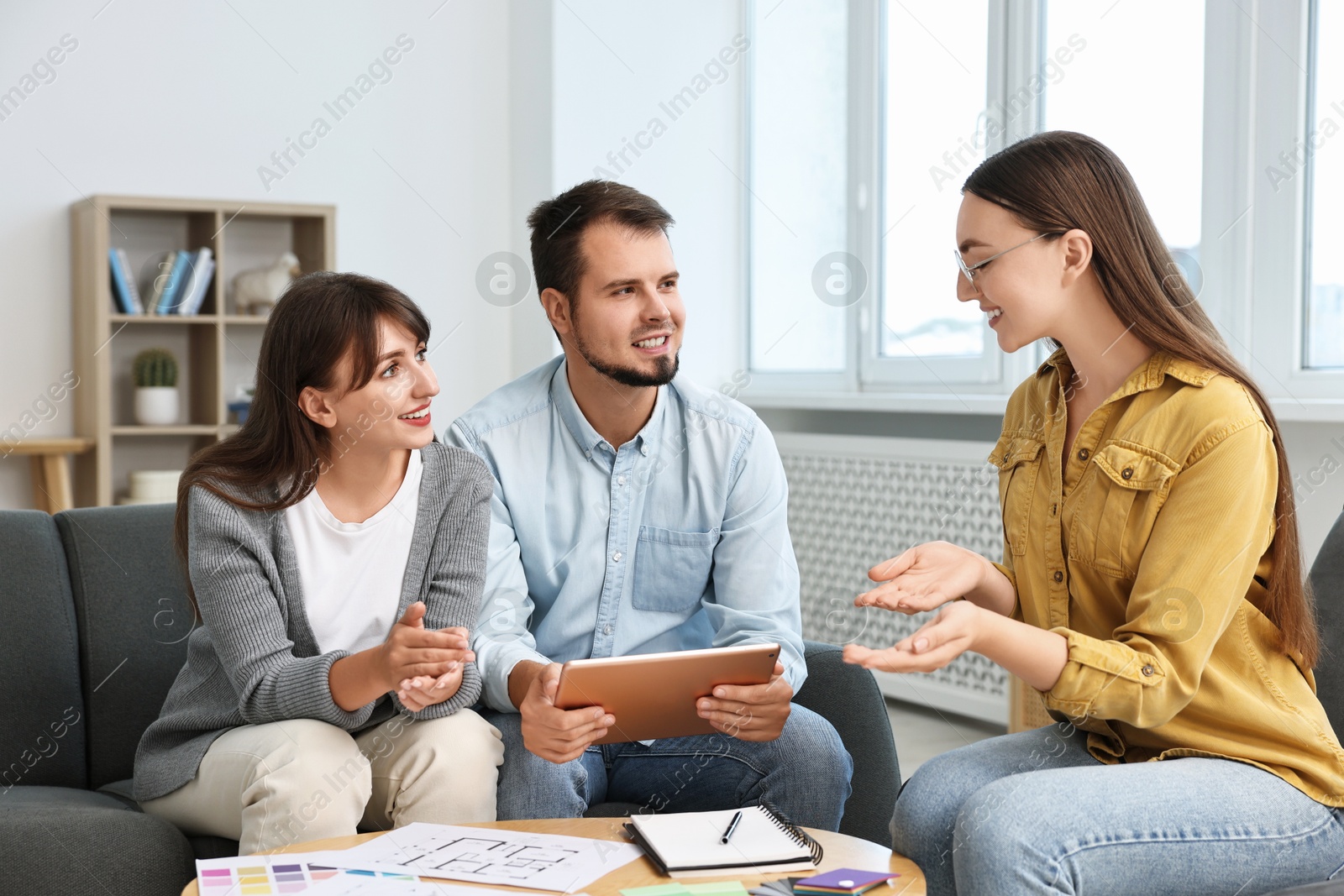 Photo of Designer discussing project with clients at table in office