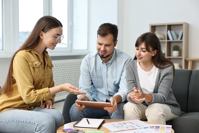 Photo of Designer discussing project with clients at table in office