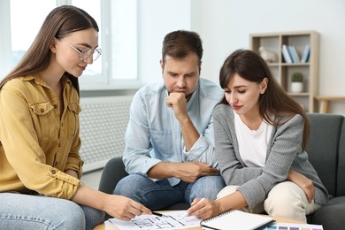 Photo of Designer discussing project with clients at table in office