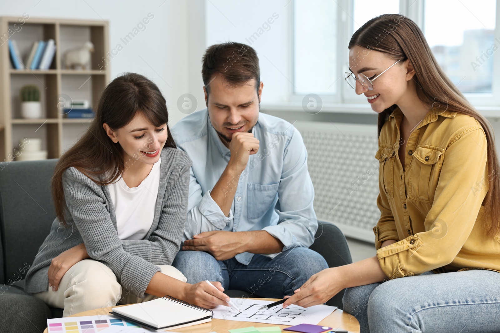 Photo of Designer discussing project with clients at table in office