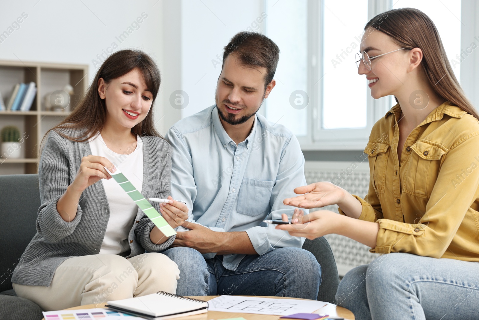 Photo of Designer discussing project with clients at table in office