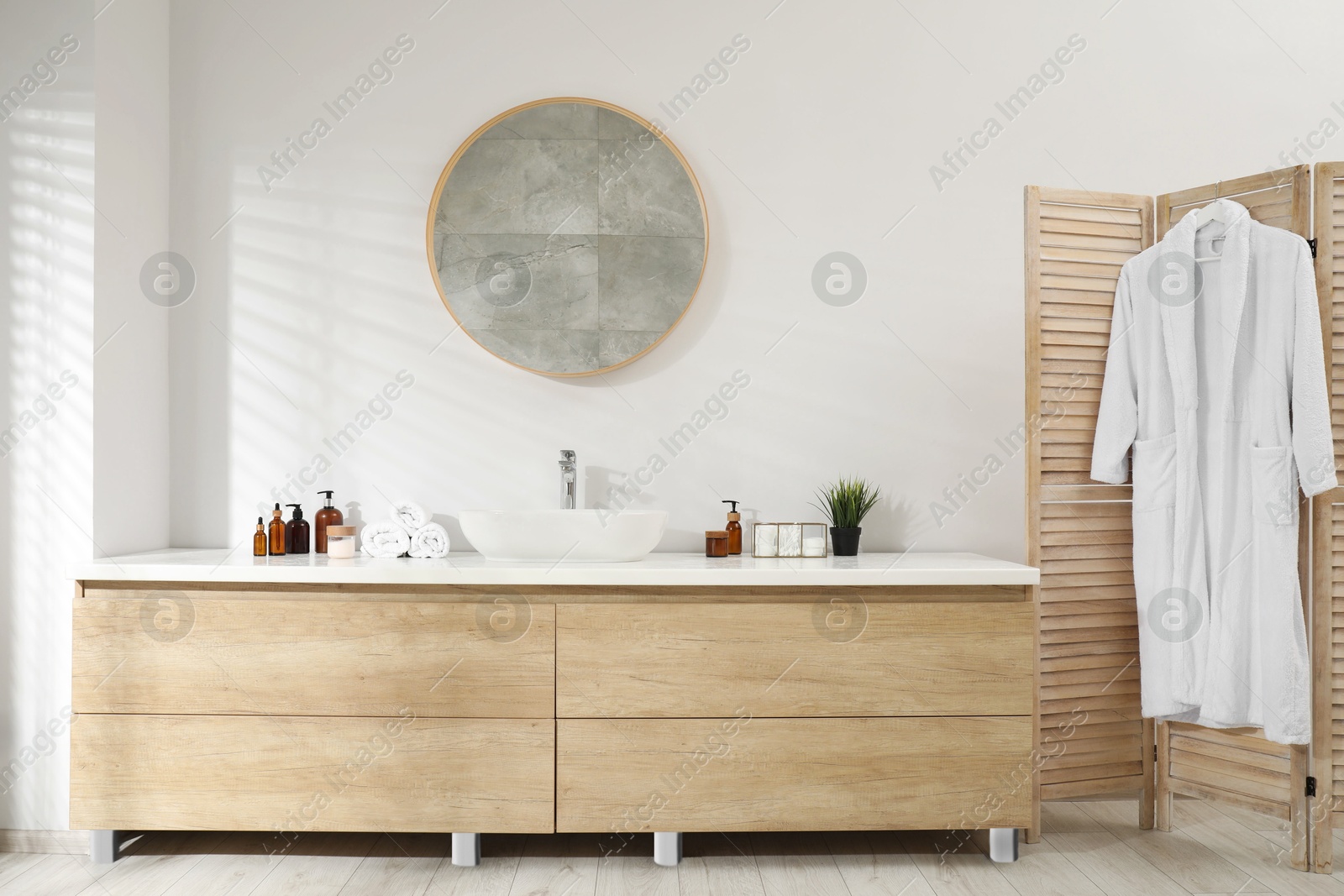 Photo of Folding screen and round mirror over sink in bathroom. Interior design