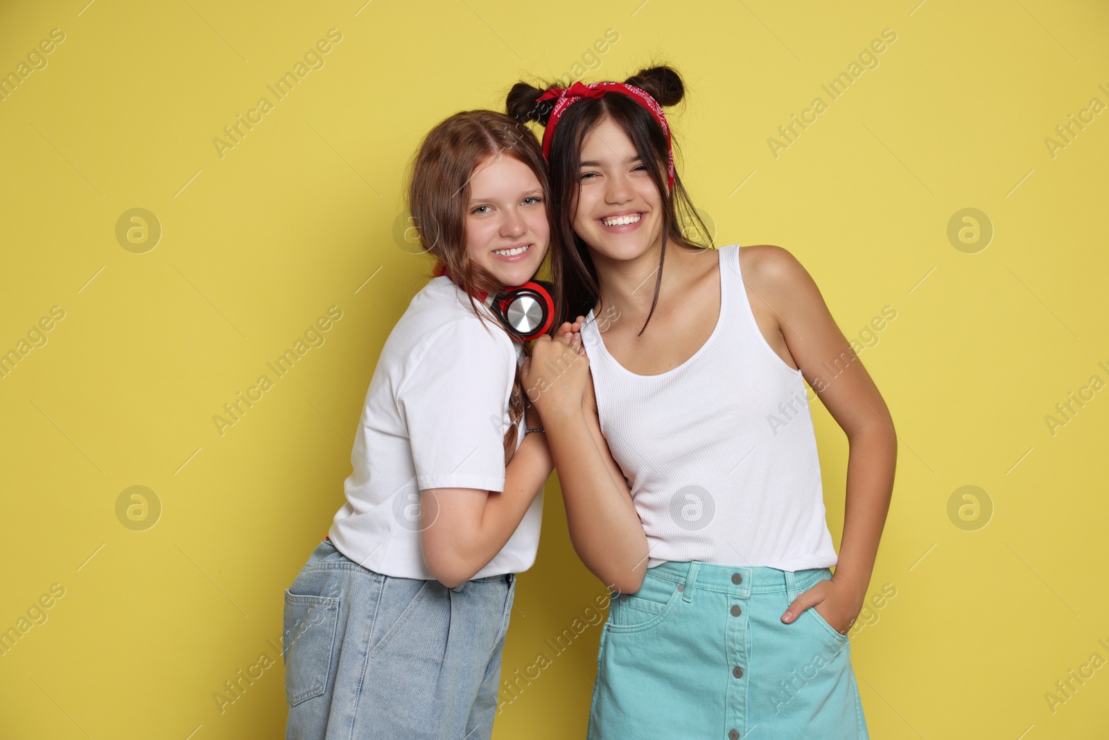 Photo of Happy teenage girls posing on yellow background