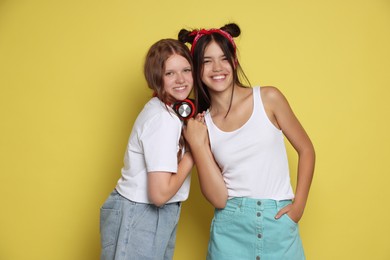 Happy teenage girls posing on yellow background