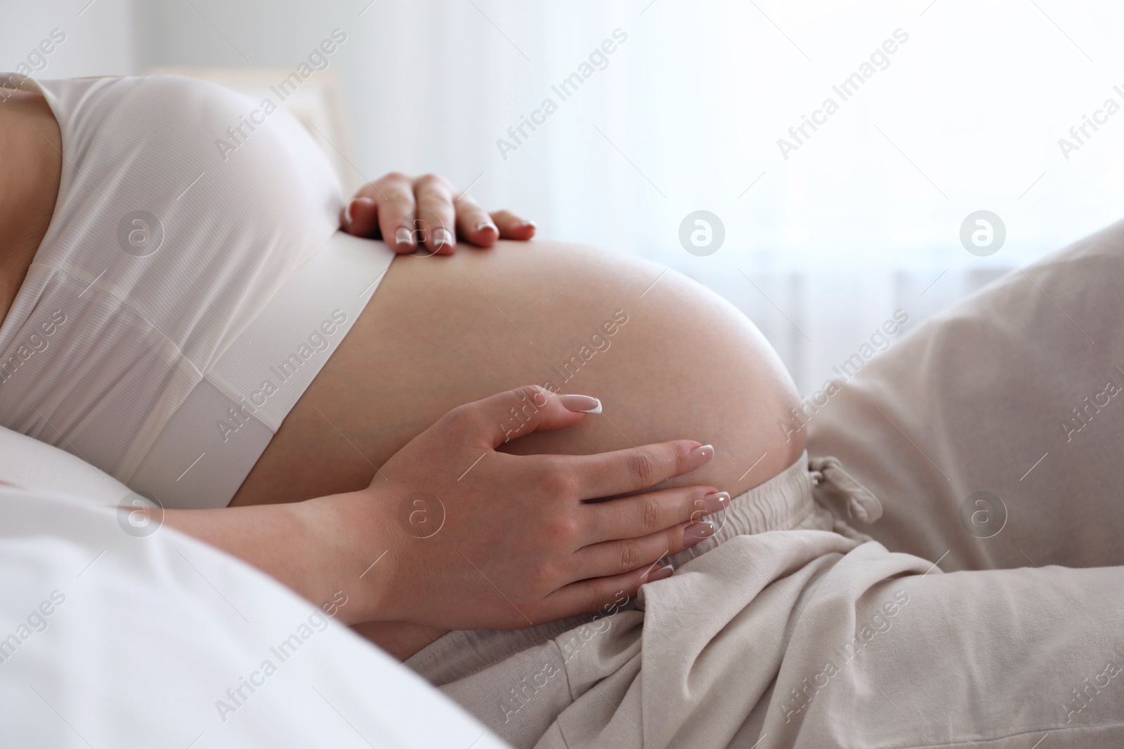 Photo of Young pregnant woman lying on bed at home, closeup