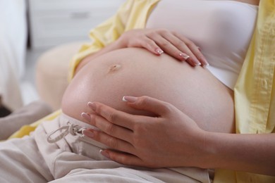 Photo of Young pregnant woman lying on bed at home, closeup