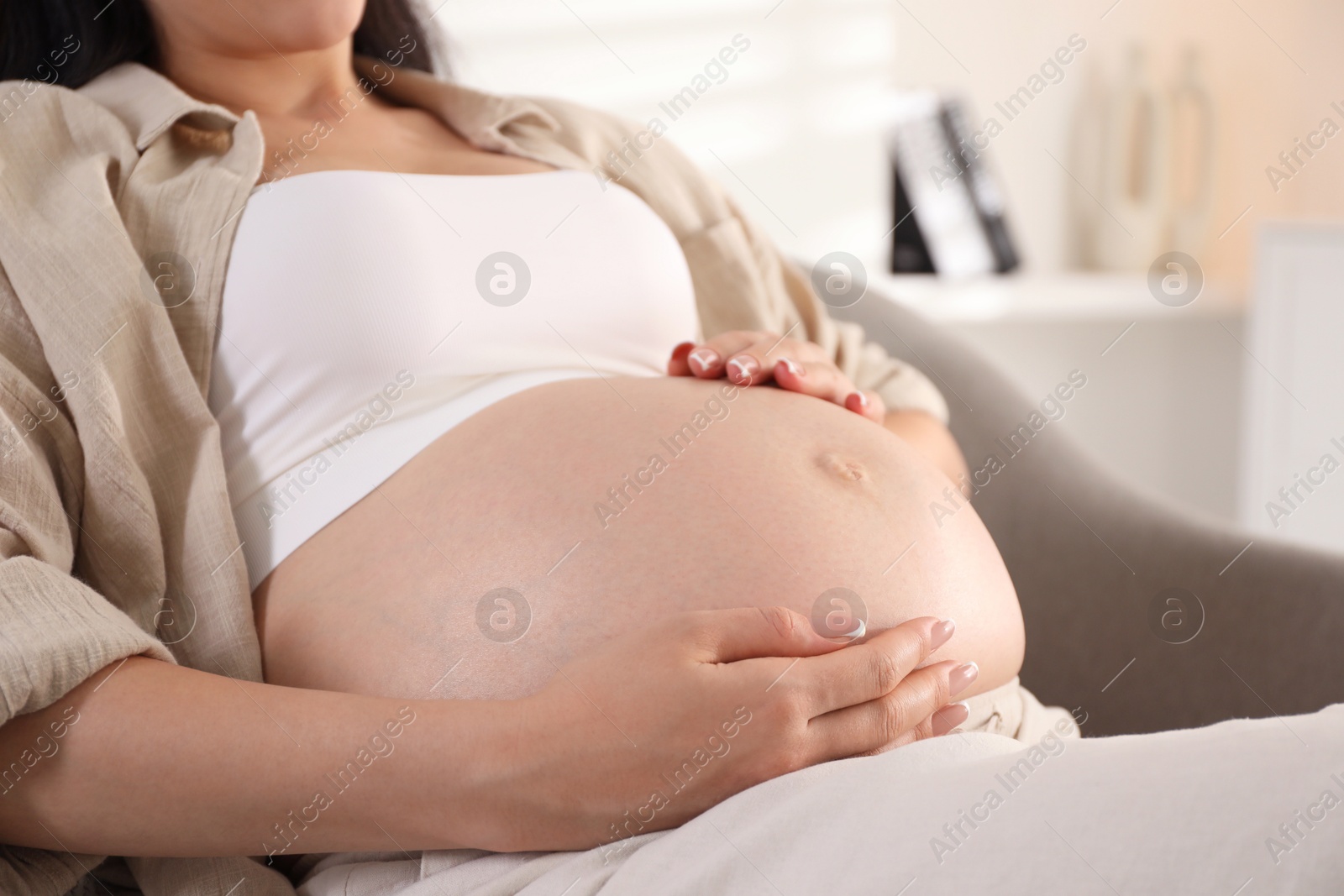 Photo of Young pregnant woman lying on bed at home, closeup