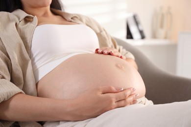 Photo of Young pregnant woman lying on bed at home, closeup