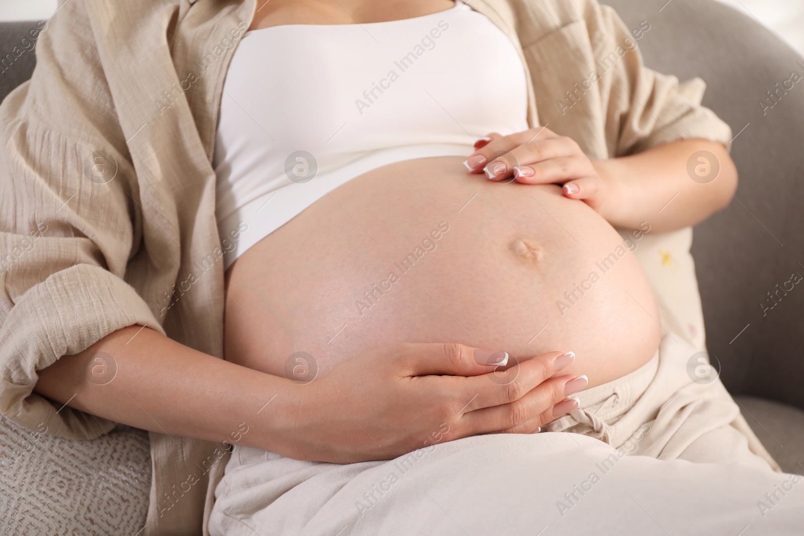 Photo of Young pregnant woman lying on bed at home, closeup