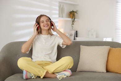 Teenage girl in headphones on sofa at home