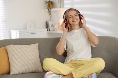 Photo of Teenage girl in headphones on sofa at home