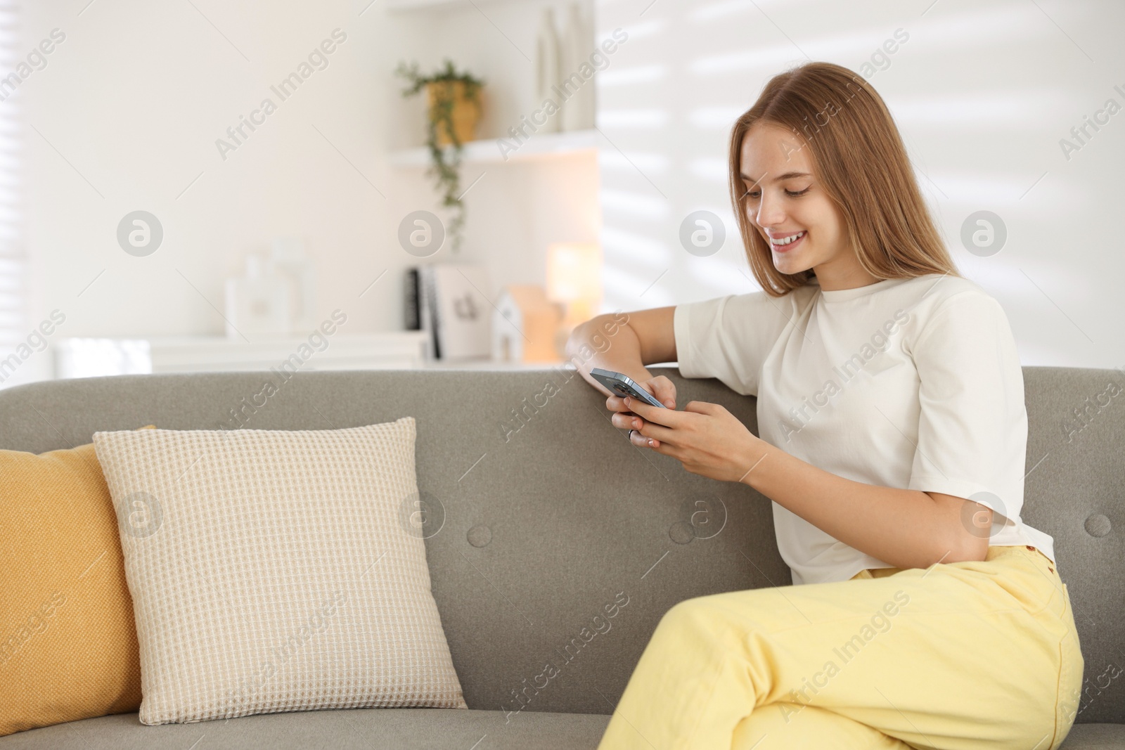 Photo of Teenage girl using smartphone on sofa at home