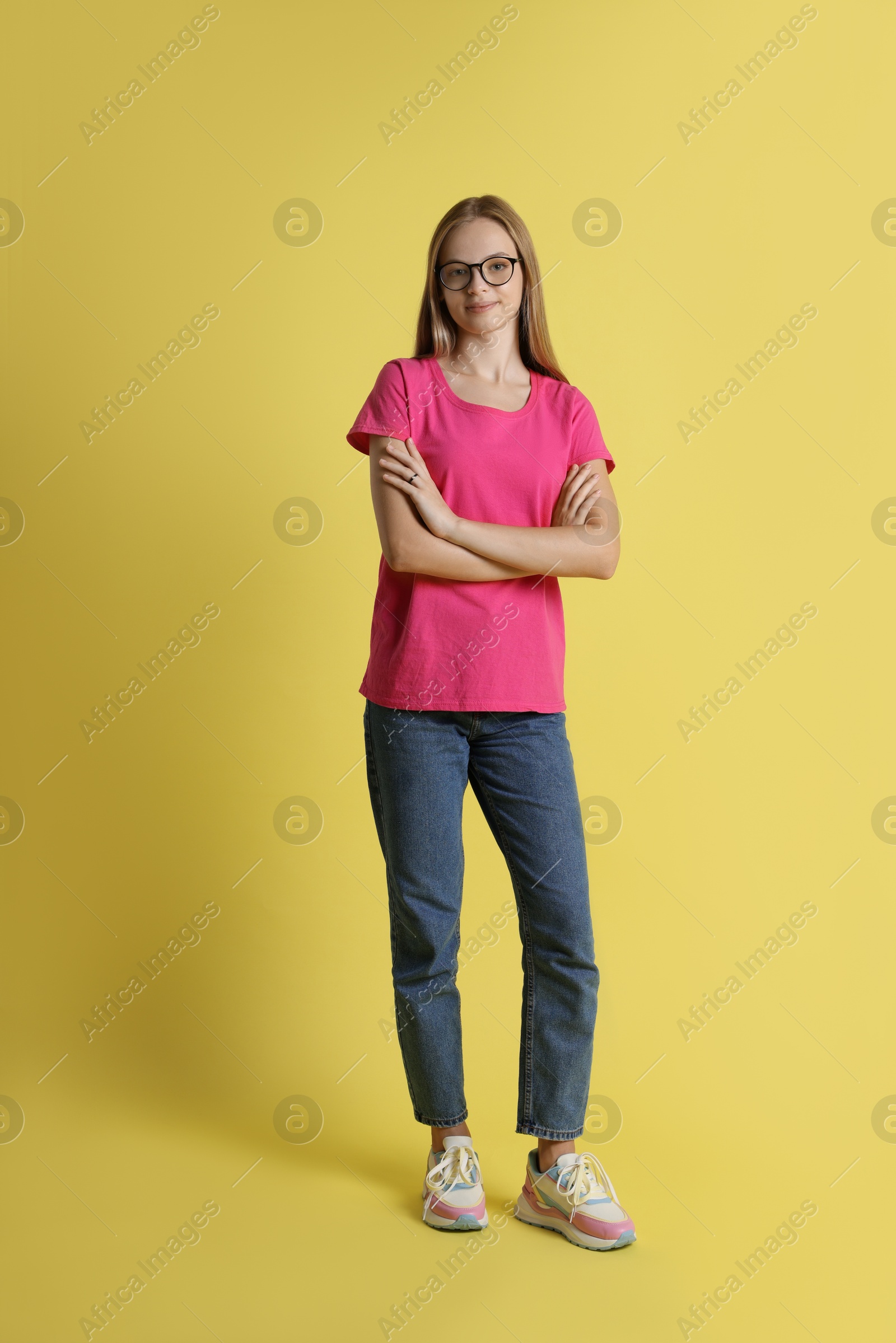 Photo of Full length portrait of teenage girl in glasses on yellow background