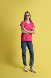 Photo of Full length portrait of teenage girl in glasses on yellow background