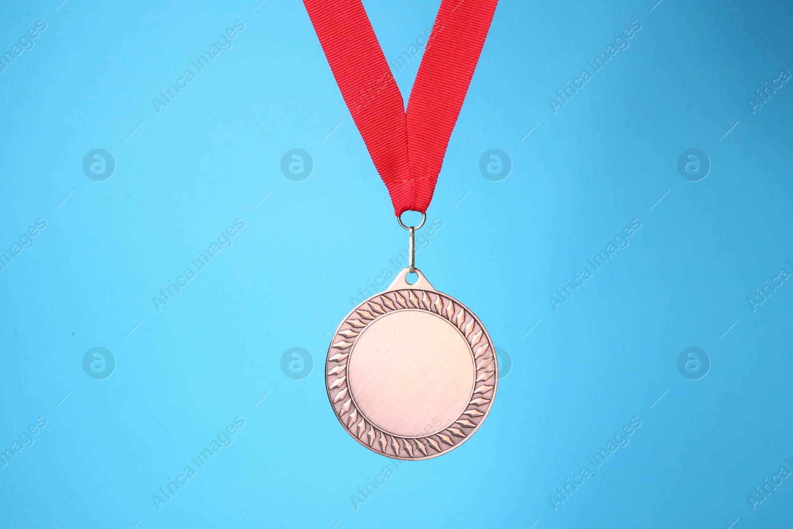 Photo of One bronze medal with ribbon on light blue background