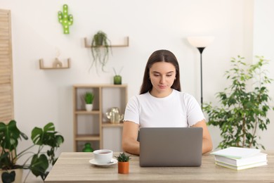 Photo of Student studying with laptop at wooden table indoors