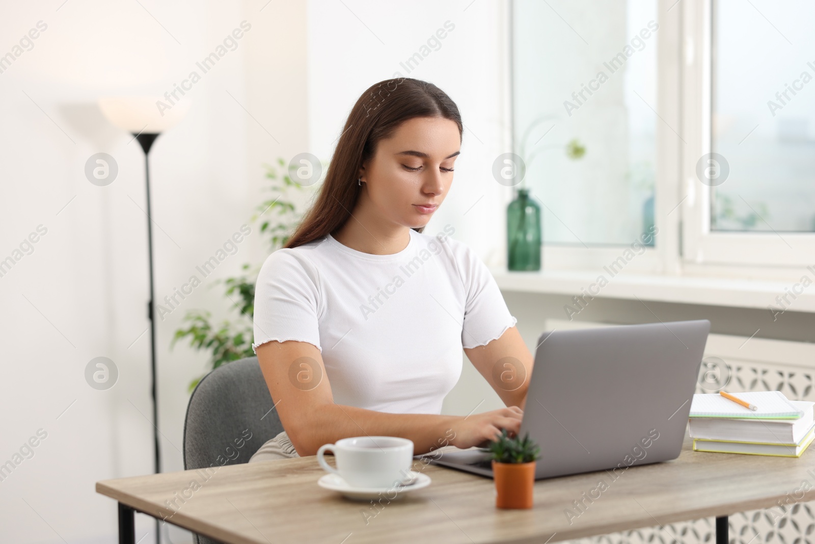 Photo of Student studying with laptop at wooden table indoors